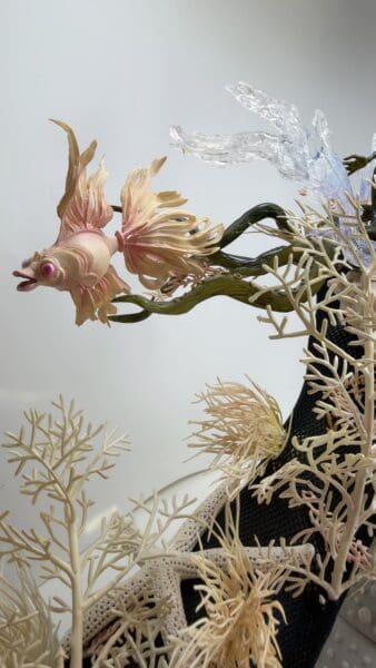 Decorative pink fish amid coral and glass sea creature