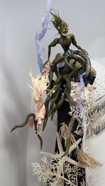 Green sea monster figurine with coral and translucent water effects