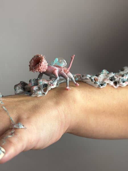Tiny fantasy creature sculpture standing on a person’s hand