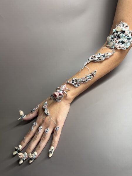 Hands covered in colourful slime and miniature decorative objects