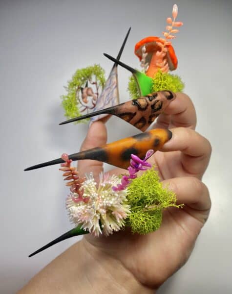 Hand displaying intricate fantasy floral stiletto nail art