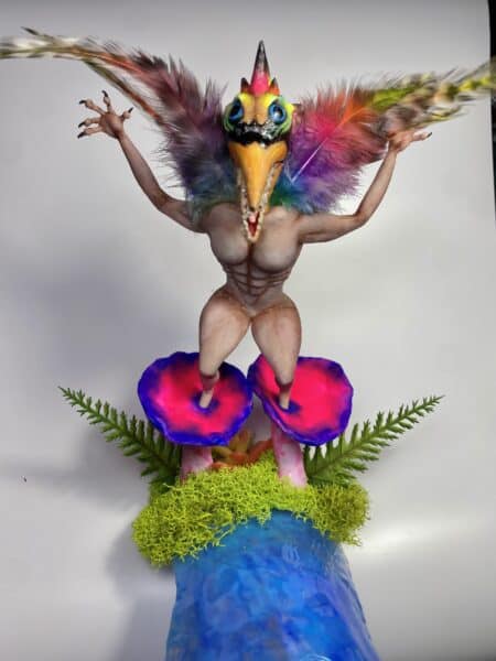 Colourful feathered creature sculpture on mushroom-shaped pedestal