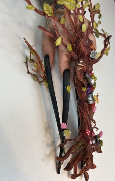 Hand holding whimsical tree-themed dangling earrings