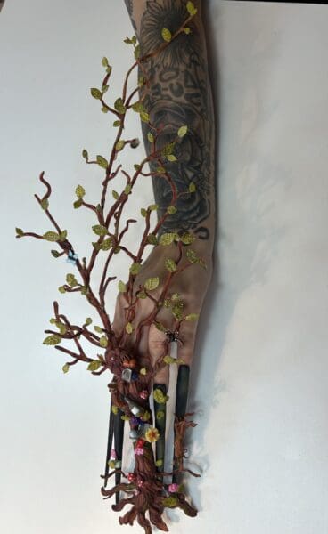 Tattooed hand wearing an ornate woodland tree sculpture