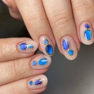 Nude nails with blue gemstone and gold outline designs