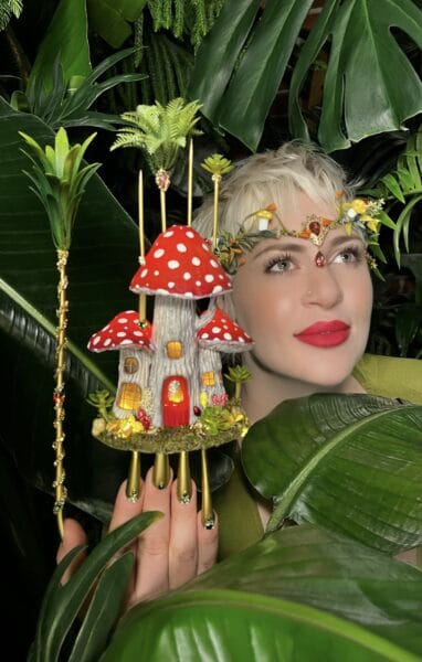 Woman with fairy mushroom house amid tropical foliage