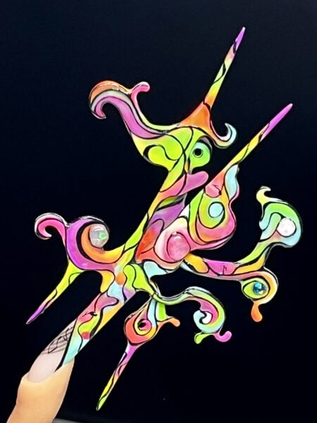 Hand with colourful abstract acrylic nails against black background