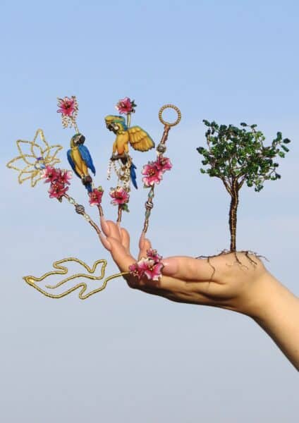 Hand wearing elaborate parrot and wire tree finger jewellery