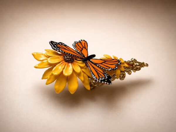 Monarch butterfly ornament on yellow flower and ornate gold bracelet