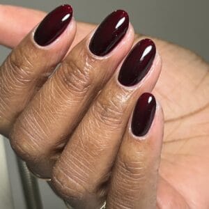 Glossy deep burgundy almond-shaped manicure on hand