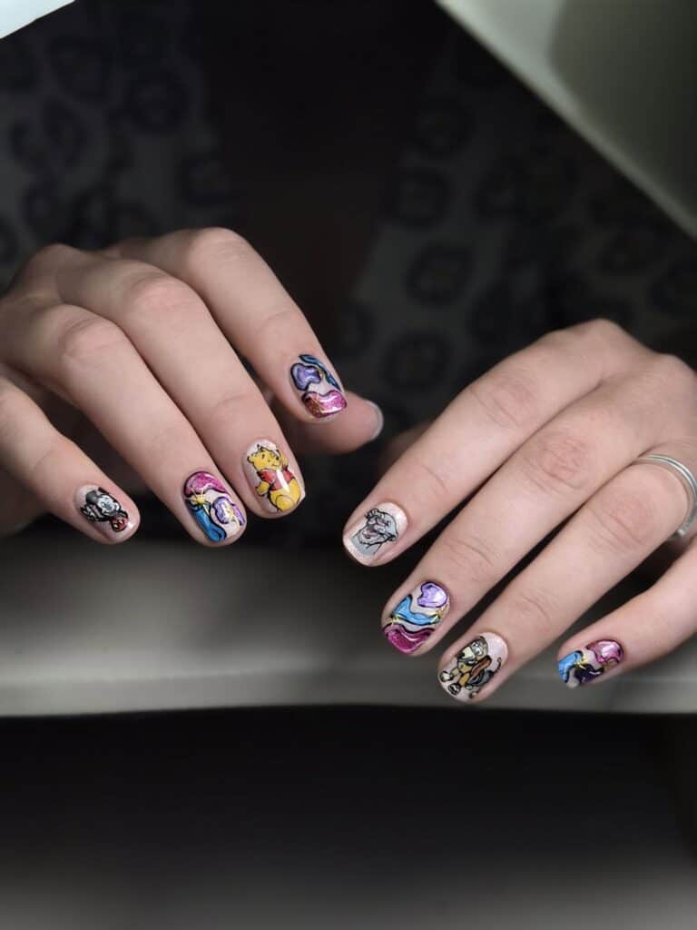 Hands displaying colourful Winnie-the-Pooh character nail art