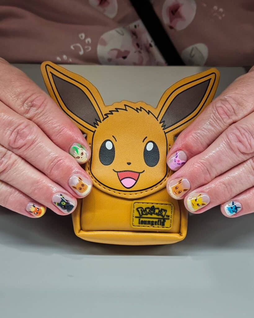Hands with Pokémon nail art holding Eevee Loungefly backpack
