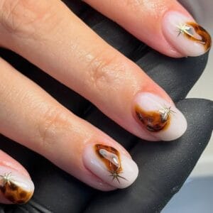 Glossy tortoiseshell nail art with gold star accents