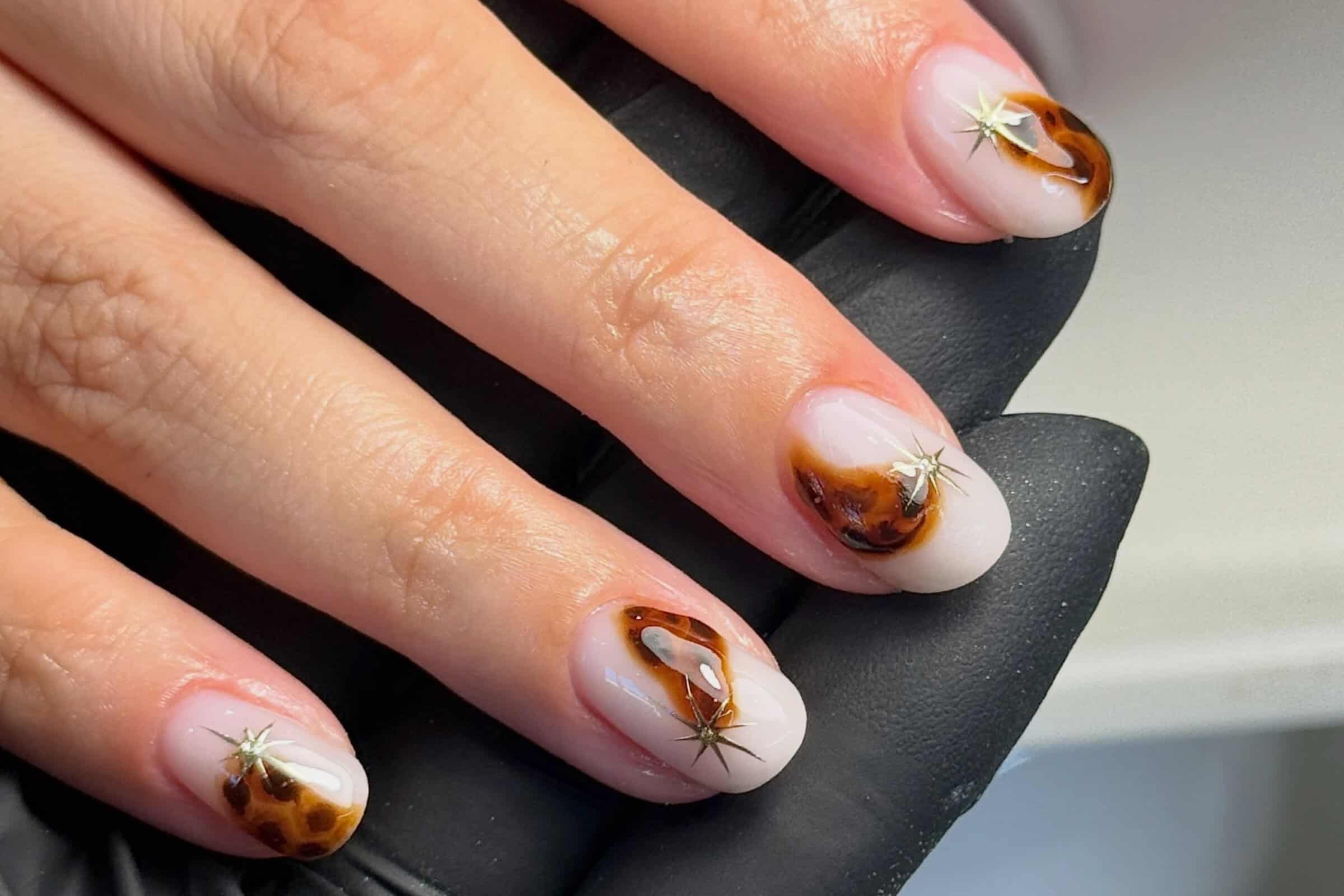 Glossy tortoiseshell nail art with gold star accents