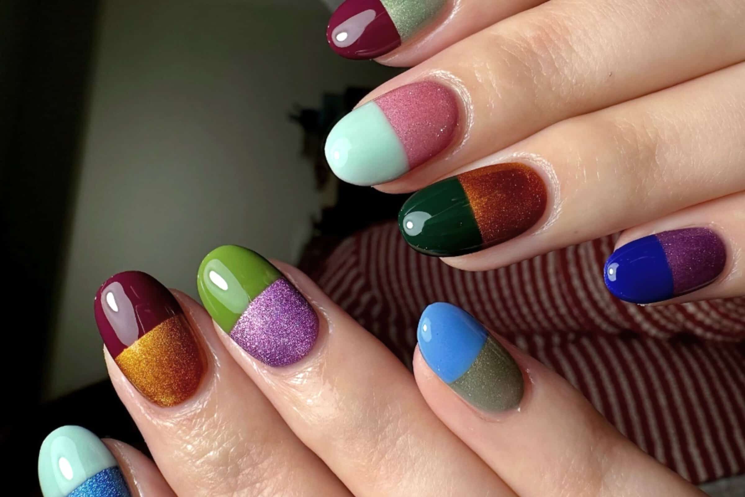 Hands displaying colourful two-tone glitter and glossy nail art